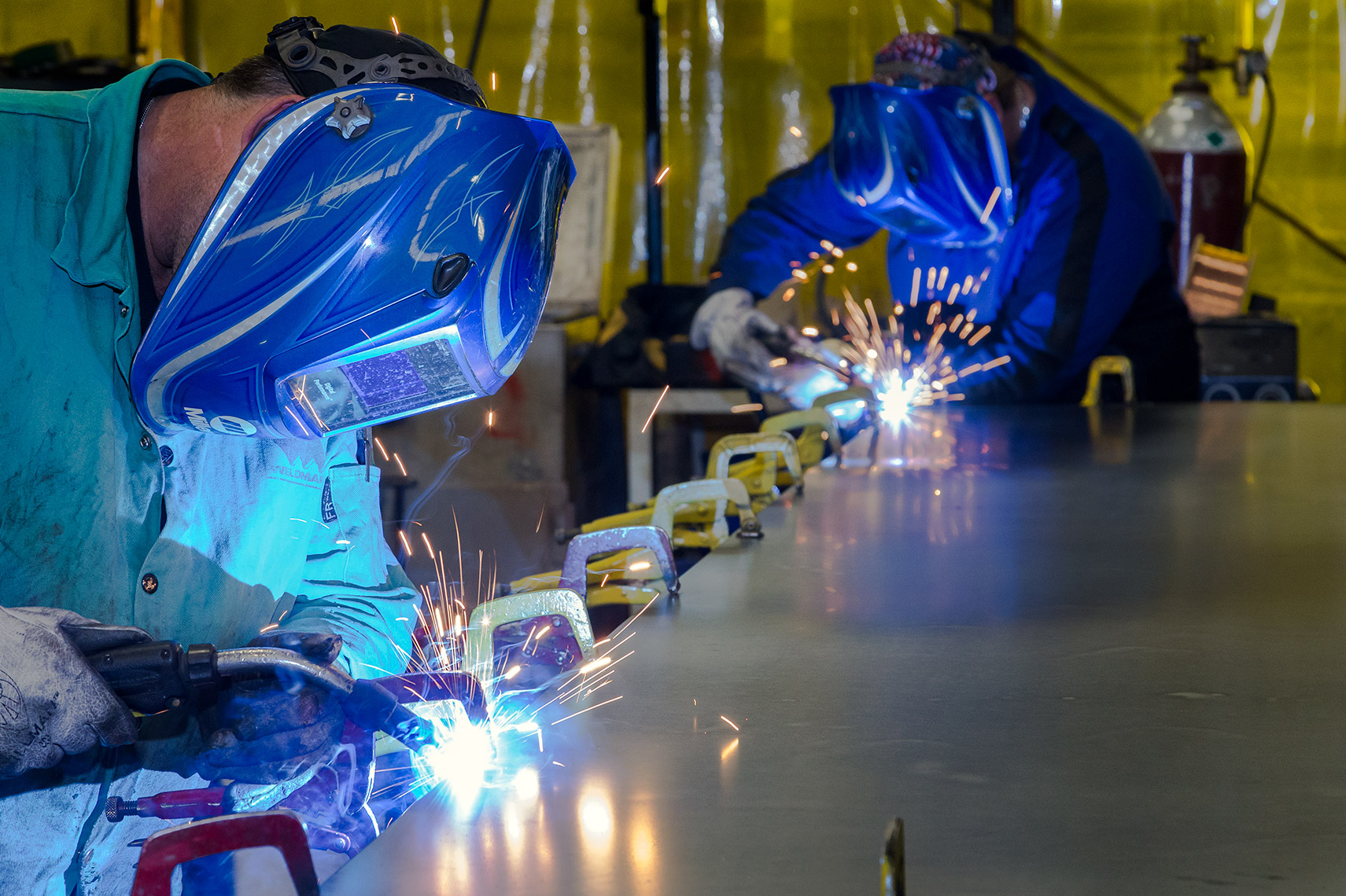 alternate view of welders at a robotics fabrication facility